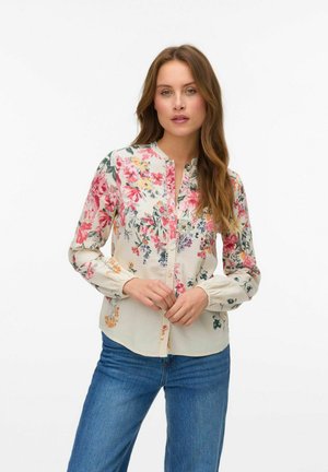Floral blouse in lightweight fabric, featuring pink, yellow, and blue flowers on a cream background. Button front and elastic cuffs.