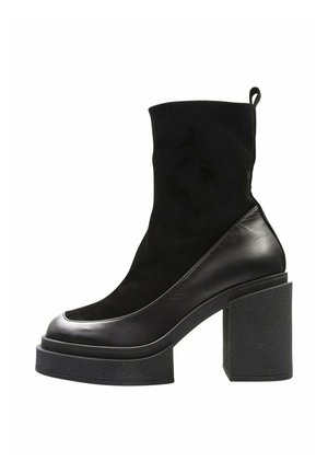 Botín negro con una combinación de materiales de cuero y ante, puntera redondeada y un grueso tacón de bloque texturizado.