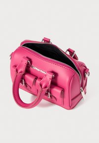 Pink leather handbag with a rounded shape, silver zipper, dual short handles, and front pouch detail. Black interior lining.