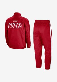 Tuta rossa dei Chicago Bulls con giacca zip-up e scritte bianche, accompagnata da pantaloni abbinati con strisce laterali bianche, realizzati in un materiale liscio.