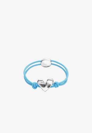 Élastique pour cheveux bleu clair avec un pendentif charmant en forme de cœur métallique argenté et une boucle ovale, présenté sur fond blanc.