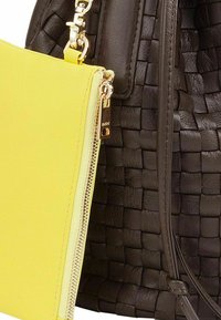 Borsa a mano in pelle intrecciata nera con una pochette in pelle gialla rimovibile. Presenta dettagli in oro e una cerniera.