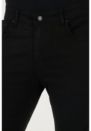 Black denim jeans featuring a fitted silhouette, classic five-pocket design, and a metallic button at the waistband. Smooth texture.