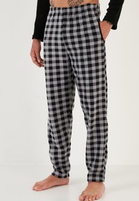 Pantalones de pijama a cuadros en negro y gris, confeccionados en una tela suave, con una cinturilla elástica y dos bolsillos laterales, diseño de pierna recta.