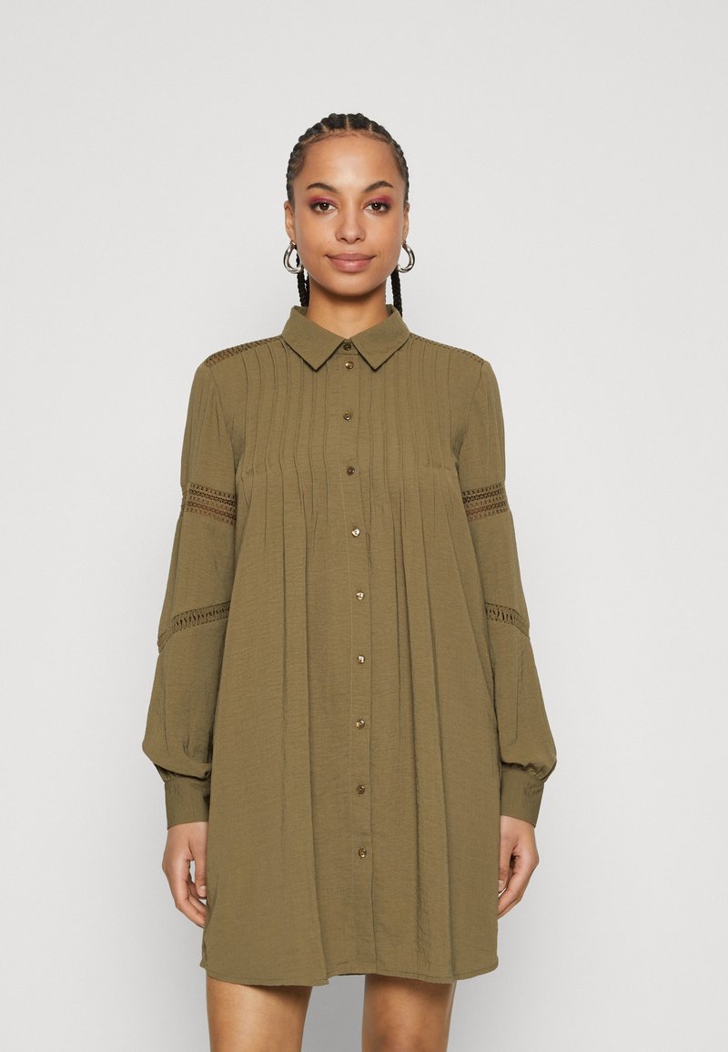 Olive green shirt dress with a button-down front, collared neck, and flared sleeves, featuring textured detailing and lace accents on sleeves.