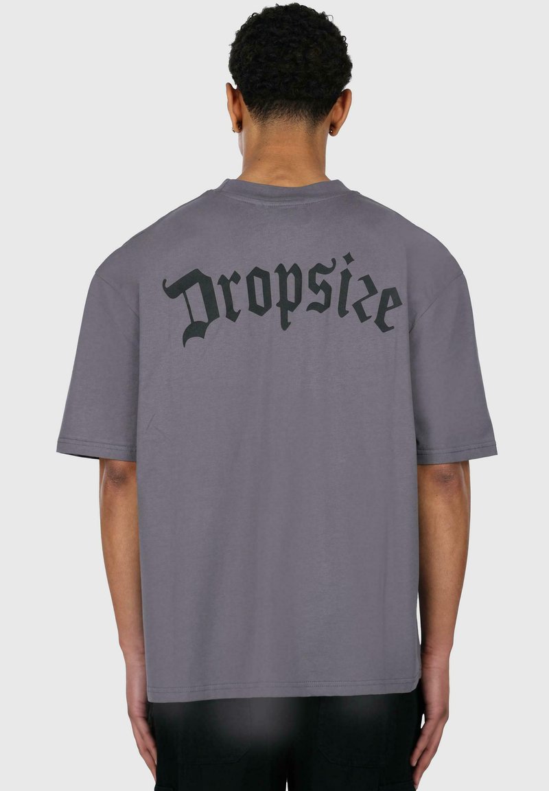 Grå crewneck t-shirt med et stort sort "Dropsize" grafik på ryggen. Fremstillet af blødt bomuld med korte ærmer og en afslappet pasform.