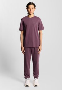 Purple cotton t-shirt and matching sweatpants set, featuring a crew neckline, short sleeves, and a minimalist logo on the chest.