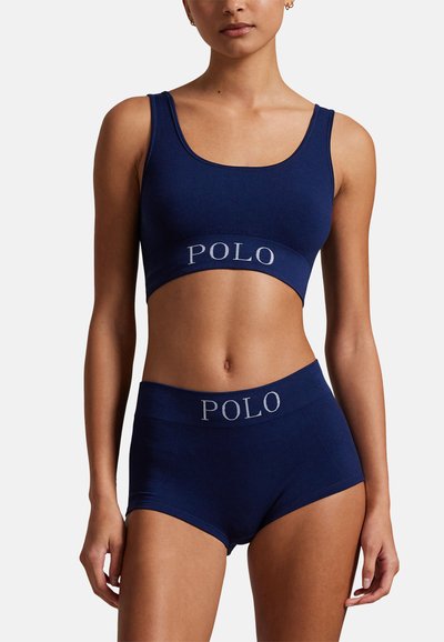 Tmavě modrý sportovní krátký top a odpovídající šortky s žebrovanou strukturou, s kontrastním logem "POLO" na pásu.