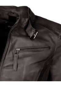 Schwarze Lederjacke mit Reißverschluss, seitlicher Reißverschlusstasche, strukturiertem Oberflächen und Schnallen-Detail am Kragen. Glattes, körpernahes Design.