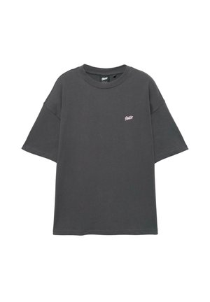 Dunkelgraues Oversize-T-Shirt aus Baumwolle mit kurzen Ärmeln und rundem Ausschnitt. Kleines rosa Logo auf der linken Brustseite.