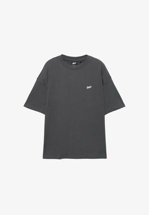 Dunkelgraues Oversize-T-Shirt aus Baumwolle mit kurzen Ärmeln und rundem Ausschnitt. Kleines rosa Logo auf der linken Brustseite.