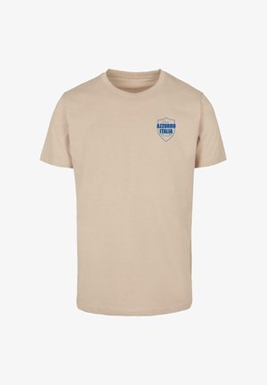 Tricou din bumbac bej cu mâneci scurte, având un logo în formă de scut albastru pe care scrie "AZZURRO ITALIA" în zona stângă a pieptului.