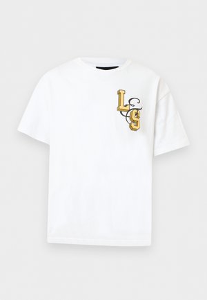 Hvid T-shirt med korte ærmer med gule 3D-stil bogstaver "L" og "S" og et sort, snørklet design på venstre brystområde.