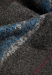 Tejido texturizado de color gris oscuro, tejido con hilos azules y blancos, que presenta fibras suaves y borrosas junto con un ligero brillo. Los patrones crean un aspecto en capas.