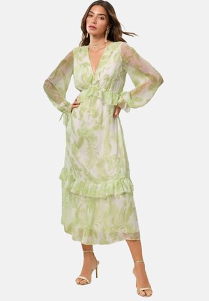 Abito maxi a stampa floreale verde chiaro con maniche lunghe trasparenti, vita arricciata e dettaglio sull'orlo. Realizzato in tessuto leggero e fluido.