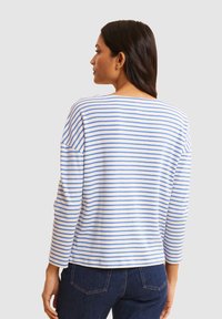 Haut à manches longues rayé en blanc et bleu clair, avec une coupe décontractée et un col rond, fabriqué en tissu doux et texturé.