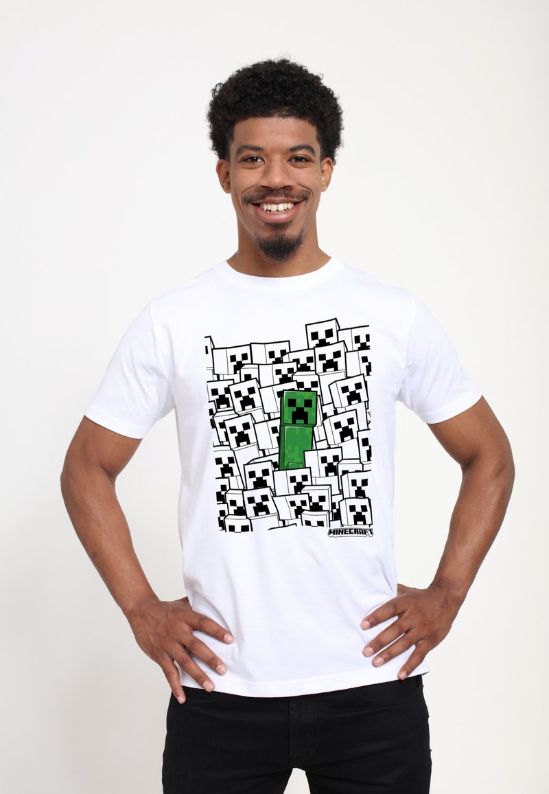 Bílá bavlněná tričko s grafickým potiskem zeleného Minecraft creepera obklopeného černobílými tvářemi postav. Krátké rukávy.