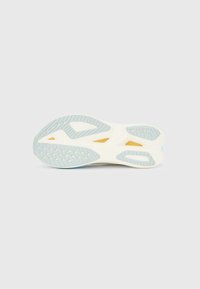 Εξωτερική σόλα παπουτσιού με κρεμώδη λευκή βάση, απαλές γαλαζοπράσινες λεπτομέρειες, υφή από καουτσούκ για πρόσφυση και στρατηγικά τοποθετημένες εγκοπές για ευκαμψία.