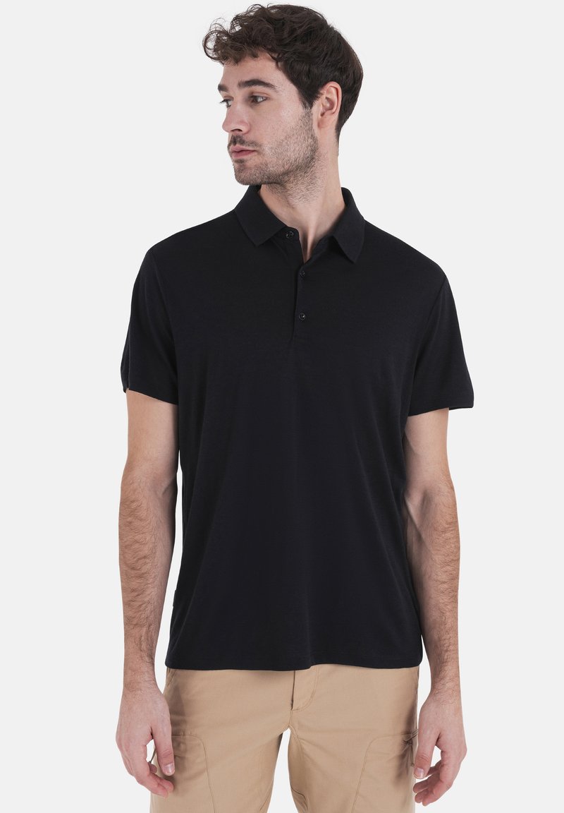 Zwarte polo met een kraag, korte mouwen en een knoopsluiting; heeft een gladde stof en een slim-fit silhouet.