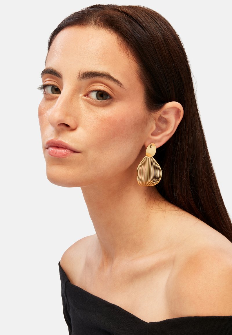 Pendientes de color dorado en forma de lágrima, con líneas verticales delgadas y un cierre circular en la parte superior.