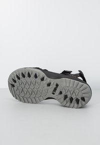 Czarny sandał z teksturowaną podeszwą, z szarą gumową podeszwą i wzorzystym gripem zapewniającym przyczepność. Regulowane paski wykonane z trwałego materiału.