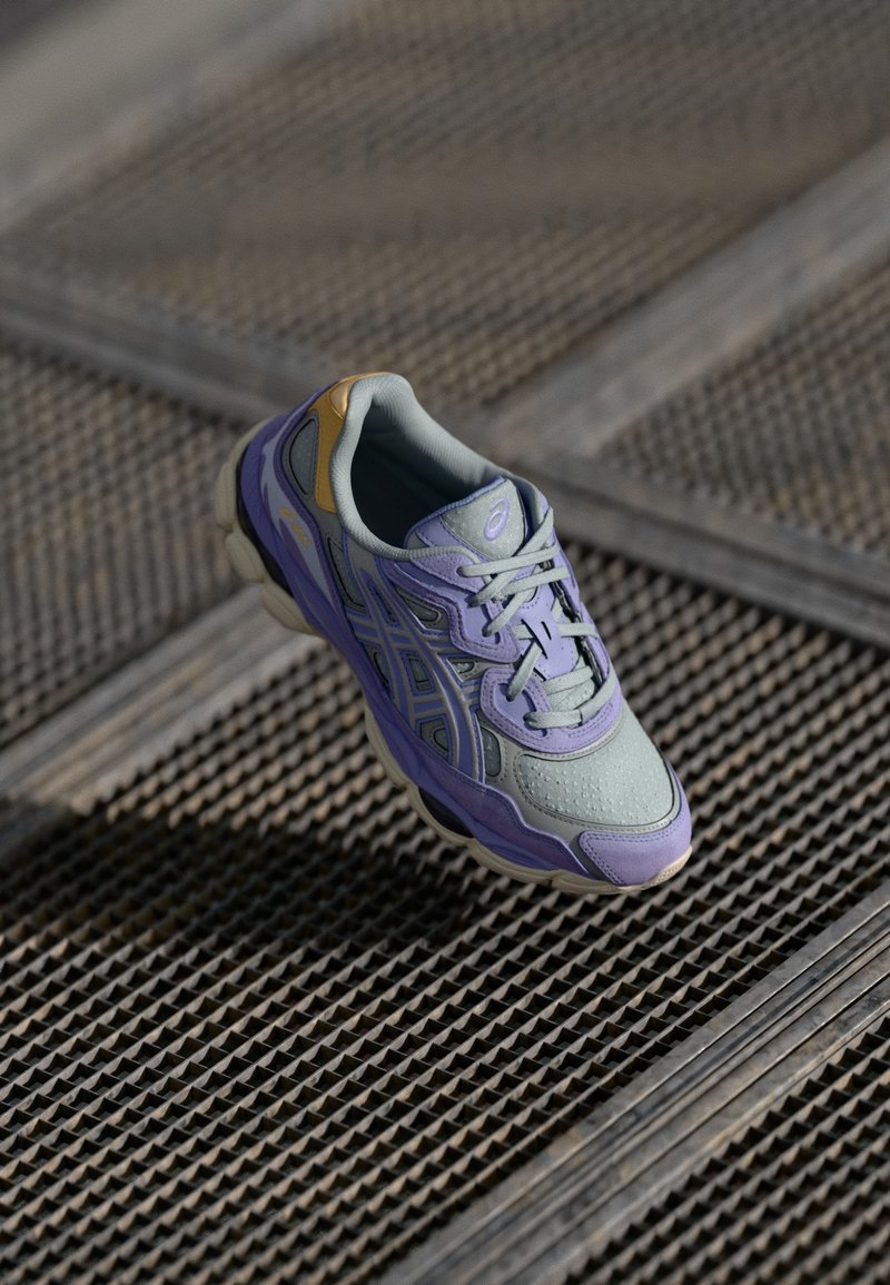 Lichtgrijze en lavendel sportshoe met mesh- en synthetische materialen, platte veters, gevoerde zool en gebogen ontwerp.