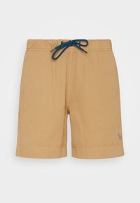 Bañadores beige con una cinturilla elástica y un cordón en color azul verdoso. Presenta un pequeño logotipo multicolor en el dobladillo. Textura de tejido suave.
