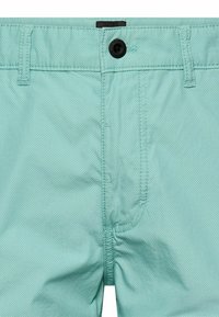 Lyse turkis shorts med lille prikmønster, sort knaplukning, bæltestropper og syet gylp detalje.