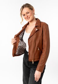 Giacca biker in pelle marrone con chiusura a zip e fodera con stampa leopardata. Presenta un colletto a scollatura e tasche laterali. Finitura testurizzata.