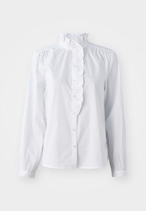 Chemise blanche à manches longues, avec un col haut froncé et un accent de volants verticaux à l'avant. Tissu en coton léger.