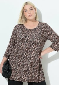 Tunika-top met luipaardprint, driekwart mouwen, ronde hals, asymmetrische zoom en een zachte, gladde textuur. Accented met een zwarte tas.
