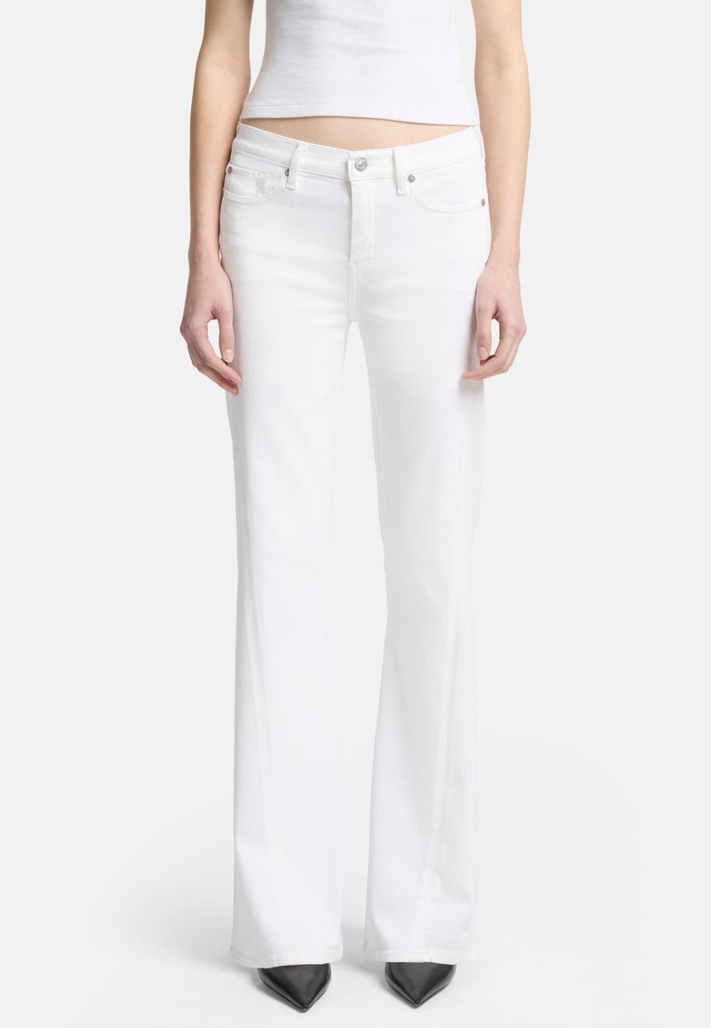 Weiße, ausgestellte Jeans aus Denim, mit einer figurbetonten Taille, standardmäßigen Taschen und einer glatten Textur. Kombiniert mit spitzen schwarzen High Heels.
