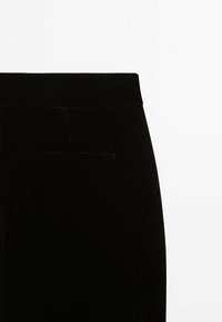 Pantalon en velours noir à la texture lisse, doté d'une ceinture et d'une poche arrière unique. Convient pour des occasions formelles ou décontractées.