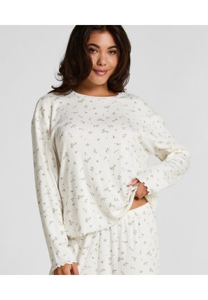 Haut à manches longues de couleur crème clair avec un petit motif floral vert, texture côtelée, encolure ronde et bords des manches festonnés. Tissu doux, coupe décontractée.