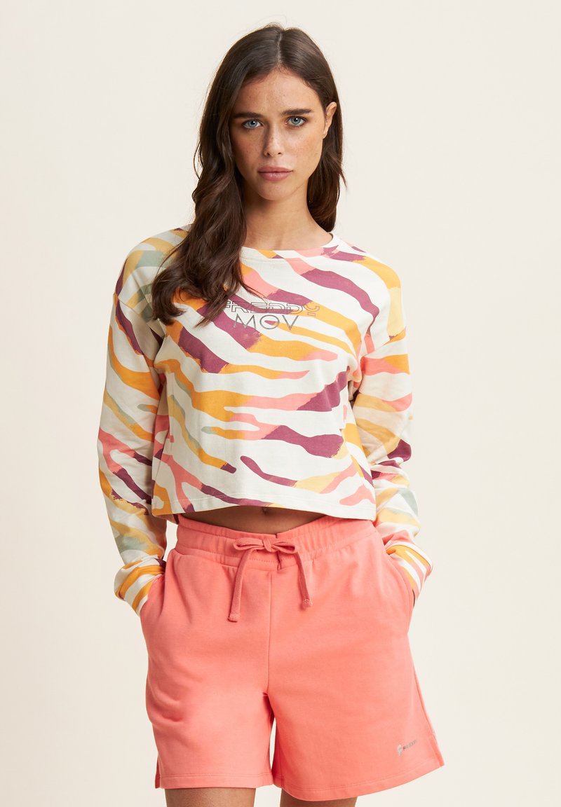 Top a maniche lunghe cropped con motivi a onde multicolore; cotone; abbinato a pantaloni corti rosa con coulisse, entrambi con vestibilità comoda.