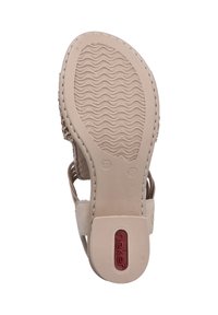 La semelle de la sandale beige présente un motif texturé avec des rainures ondulées. Un accent rouge avec la marque est visible près du talon. Taille 37 marquée.