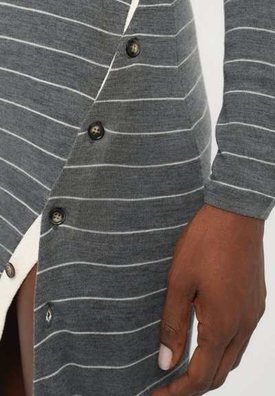 Gray striped cardigan dress featuring white horizontal stripes, round black buttons, and a side slit revealing a contrasting white interior.