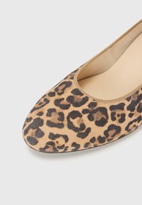 Flat sko med leopardmønster laget av myk semsket skinn, med rund tå, beige bunn med mørkebrune flekker og en glatt innersåle.
