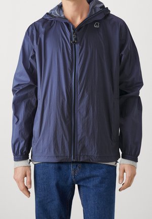 Veste coupe-vent navy avec fermeture éclair à l'avant, surface texturée et poignets ajustables. Inclus une capuche et un logo sur la poitrine.