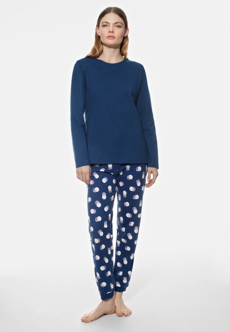 Haut à manches longues bleu marine associé à un pantalon de pyjama avec un motif de pois blancs et roses, fabriqué en coton doux. Coupe décontractée dans l'ensemble.