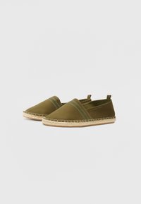 Green canvas slip-on shoes with two blue stripes, woven jute trim, and elastic side accents for flexibility. Flat sole for comfort.