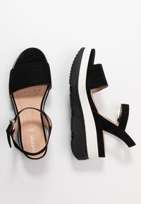 Sandali platform in suede nera con cinturino alla caviglia regolabile, dotati di suola in gomma nera e intersuola bianca. Fodera interna liscia.