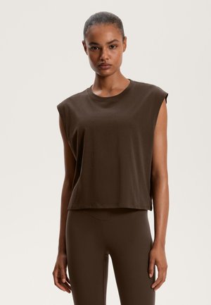 Rjava brezrokavna majica skrajšanega kroja iz mehkega bombaža, s krožnim ovratnikom in sproščenim rezom. Vzporedno rjava legging hlače.