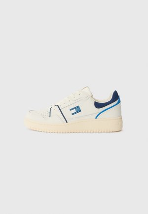 Biały niski sneaker z perforowanym noskiem, niebieskimi akcentami i etykietą z logo po boku, wyposażony w kremową gumową podeszwę i wyściełany kołnierz.