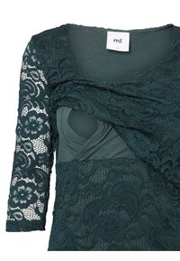 Donkergroene jurk met kanten mouwen met bloemmotieven, een nauwsluitend lijfje en een gelaagd stoffen ontwerp dat textuur en visueel belang creëert.