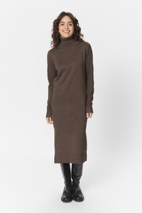 Robe en tricot marron à col roulé, manches longues, ajustée, avec des poignets côtelés, atteignant le mi-mollet, associée à des bottines noires.