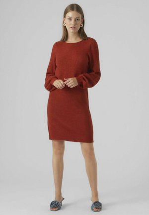 Robe en tricot rouge à manches longues, avec un col rond et une coupe décontractée, présentant une texture douce et une longueur mi-cuisse. Une paire de chaussures à talons bleues.