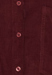 Burgundy kordfloddfabric med vertikala ränder, utrustad med fem matchande knappar och en sidoficka med sydd detalj.