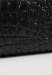 Portafoglio in pelle nera con texture, caratterizzato da un motivo in pelle di cocodrillo e il logo "LIEBESKIND BERLIN" impresso, che presenta una finitura lucida.