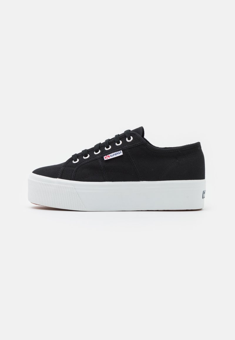 Schwarze Canvas-Sneaker mit strukturiertem Obermaterial, weißer Gummi-Plattformsohle, sechs Metallösen und einem kleinen rot-blauen Logo an der Seite.
